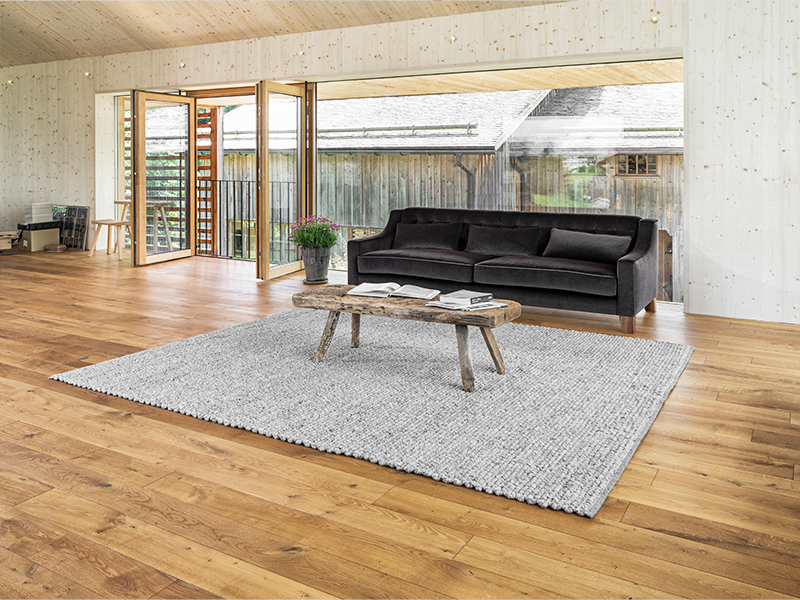Gemütliches Sofa auf einem Handwebteppich in einem Raum mit viel Holz